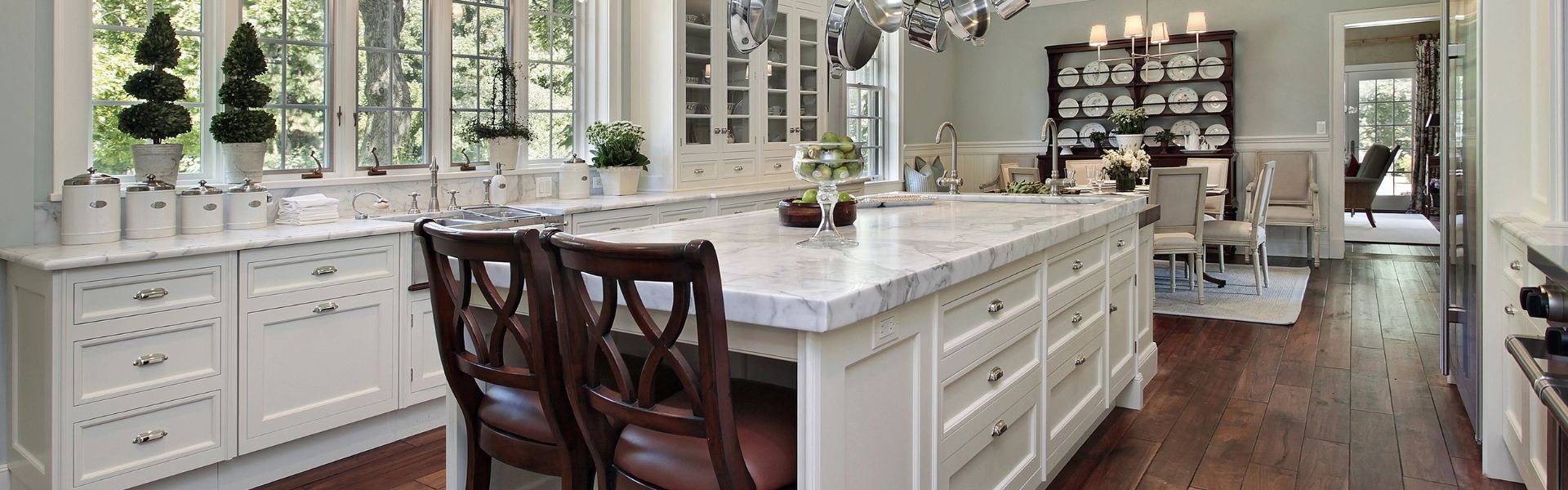 Elegant and spacious kitchen refined by Kevin Brodie Services, featuring white cabinetry, marble countertops, and stylish wooden stools in Sharon, Pennsylvania. This image highlights their skill in cabinet refinishing and luxury interior enhancements.